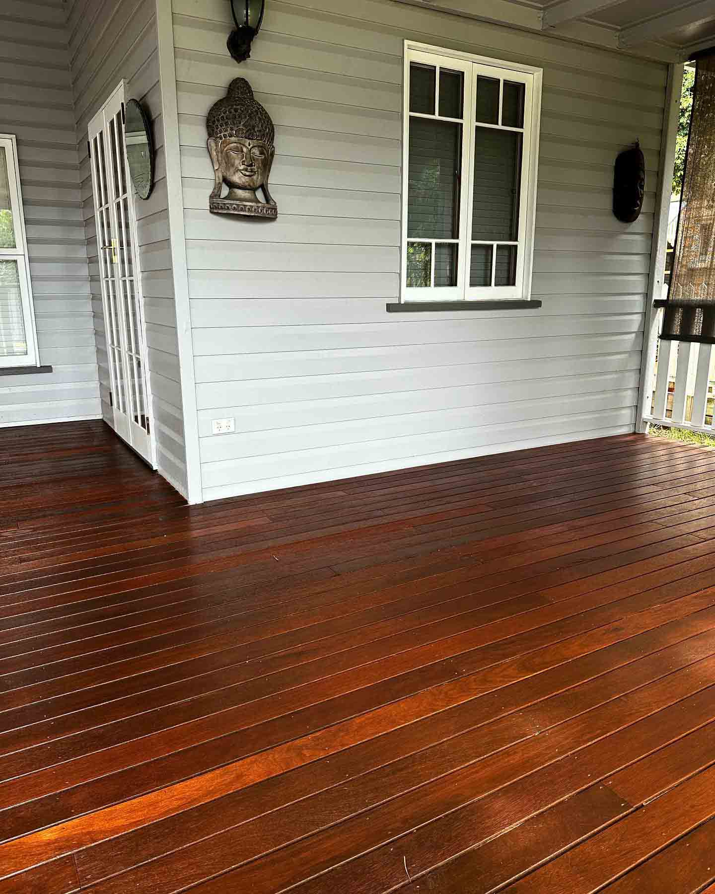 Dark oiled timber verandah against a grey weatherboard wall