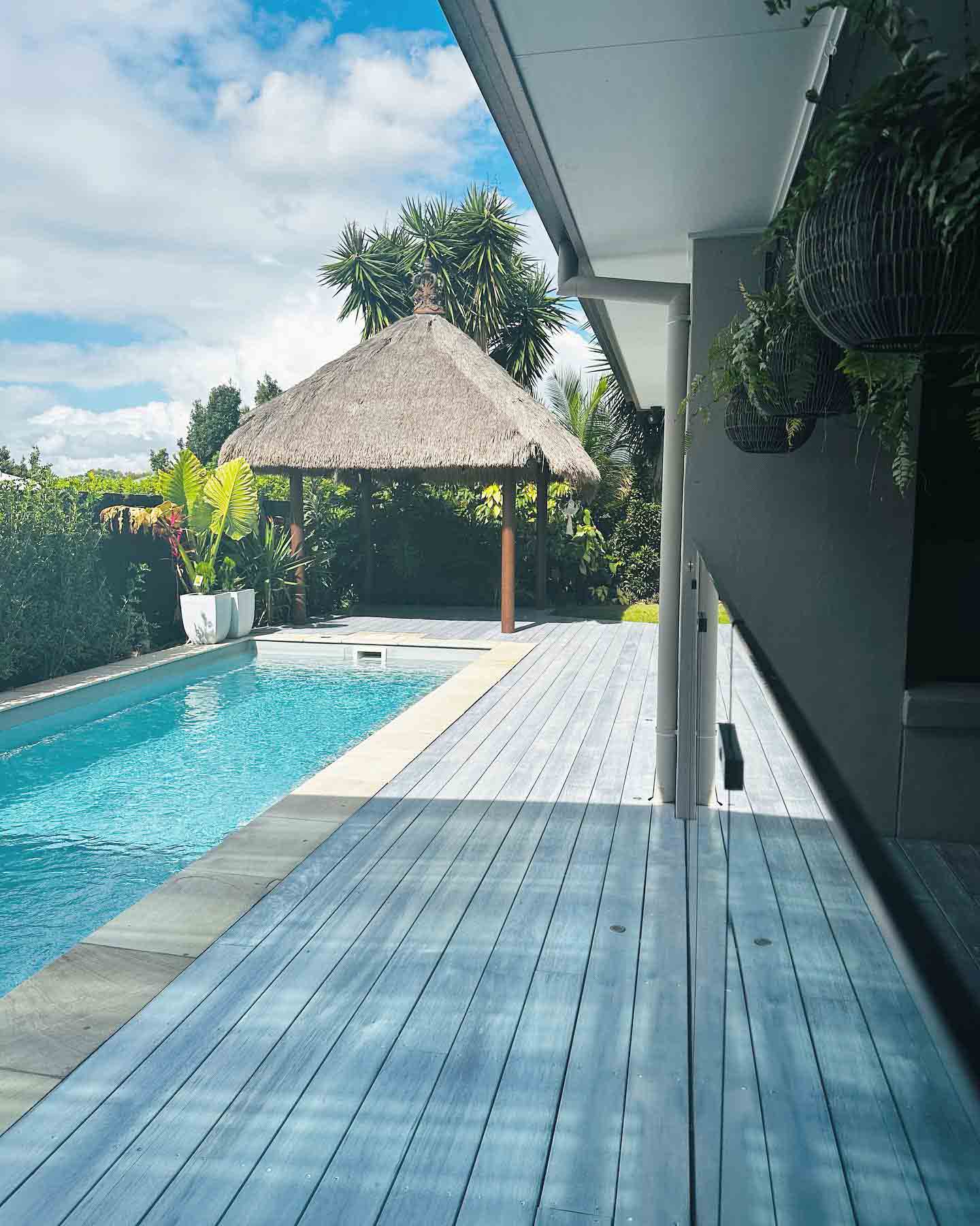 Same pale grey pool deck, looking along the lap pool to the thatched cabana